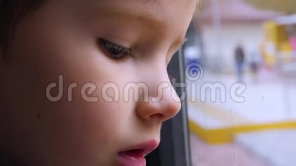 孩子在窗户里反射玻璃一个小孩在火车上向窗外看的特写镜头乘火车旅行视频的预览图