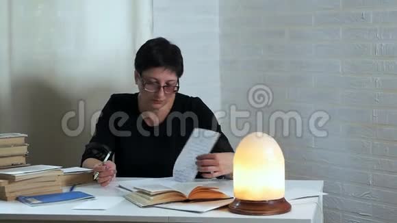 一个戴眼镜的女人手里拿着铅笔在纸上做笔记思考和思考写一首诗一首诗视频的预览图