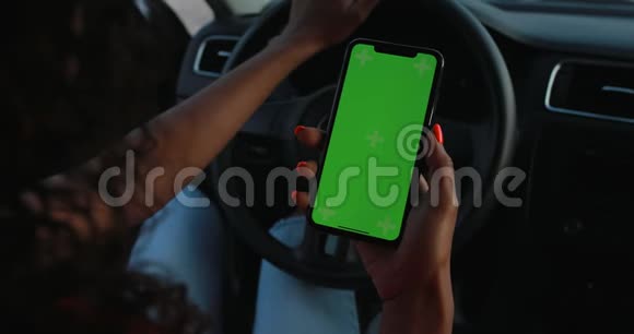 POV女司机手持智能手机空白绿色屏幕视频的预览图