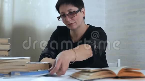 一个戴眼镜的女人手里拿着铅笔在纸上做笔记思考和思考写一首诗一首诗视频的预览图