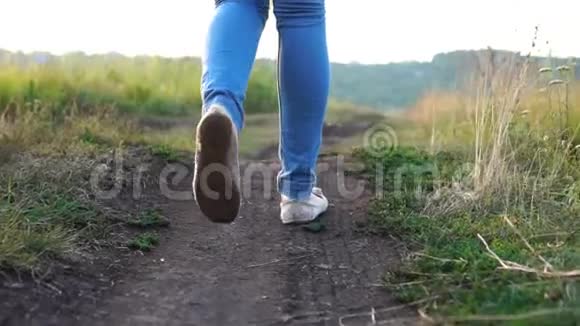 夏日穿牛仔裤腿的年轻女子走在地面道路上的后景视频的预览图