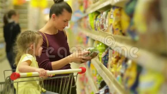 母亲和女儿在超市购物他们正在买早餐片一个女儿坐在超市视频的预览图