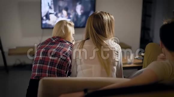 在客厅里坐在沙发上周末在电视上看电影的快乐五个朋友的后拍视频的预览图