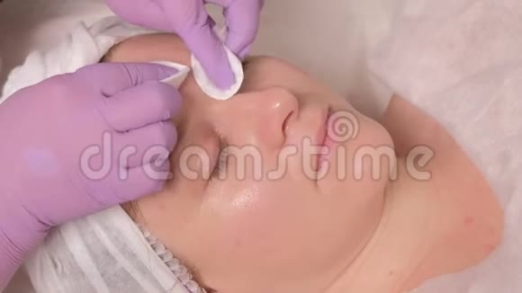 在两个电极的帮助下病人额头上的微电流穴位按压一个闭着眼睛的中年女人的脸视频的预览图