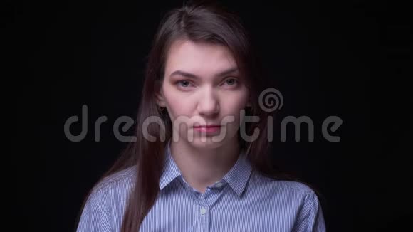 年轻的黑发女商人穿着蓝色衬衫在黑色背景下严肃地观看镜头的肖像视频的预览图