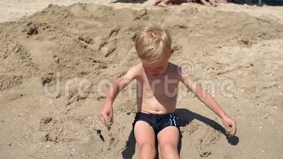 夏天小可爱的男孩坐在海边的沙滩上男孩视频的预览图