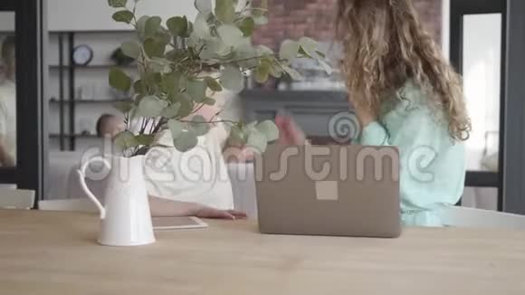 肖像紧张的年轻母亲在笔记本电脑前试图通过手机交谈而她的十几岁的儿子在奔跑中玩耍视频的预览图