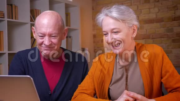 两位白发苍苍的白种人高级配偶在笔记本电脑上用视频聊天的特写照片在办公室里很开心视频的预览图