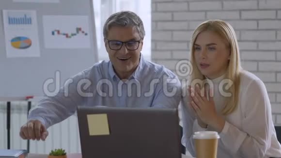 我们赢了两位成功的商人正看着电脑屏幕期待着结果的出现视频的预览图
