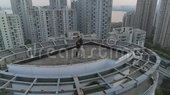 空中轨道拍摄拥抱和亲吻的夫妇在屋顶上的现代公寓大楼在日落视频的预览图