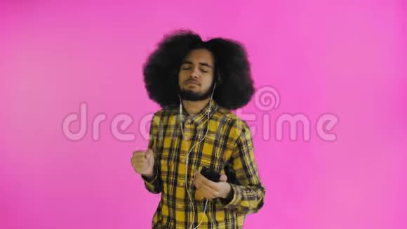 积极的非裔美国人用电话听音乐在他的耳机紫色背景情感概念视频的预览图