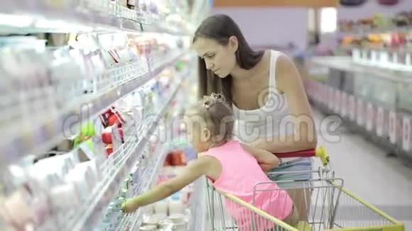 年轻女子带着可爱的女儿在杂货店买酸奶视频的预览图