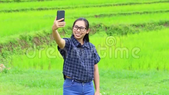 亚洲年轻女子自拍与智能手机在特伦德稻田视频的预览图