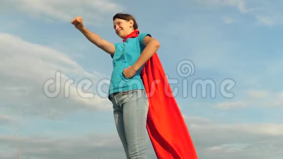 女孩梦想成为超级英雄对抗蓝天站在红色斗篷里的年轻女孩表达了梦想美丽美丽视频的预览图