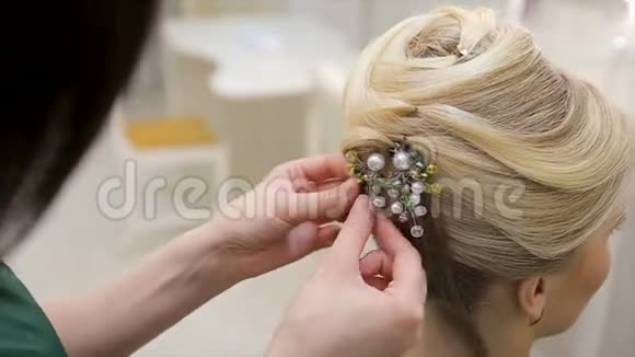 理发师给一位年轻的金发女子的头发贴上了一种装饰这是一种特写视频的预览图