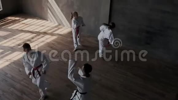 一组穿着白色和服的熟练运动员同步进行一套跆拳道腿踢操战斗视频的预览图