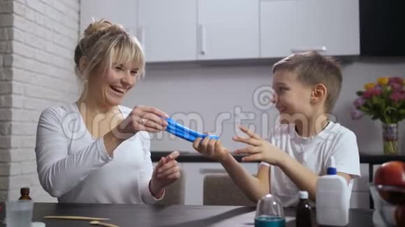快乐的妈妈和儿子一起伸展手工黏液视频的预览图
