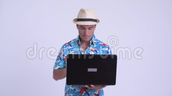 年轻快乐的西班牙裔游客在使用笔记本电脑时思考视频的预览图