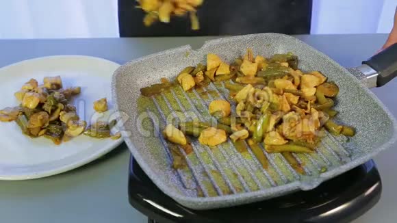 一个女人把炸鸡和青豆和蘑菇从煎锅变成了白色盘子视频的预览图