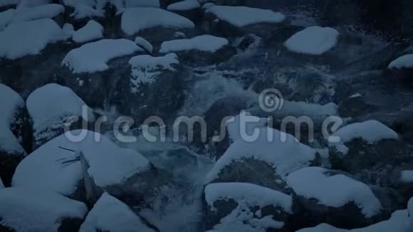 雪在晚上落在岩石河上视频的预览图