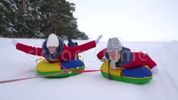 快乐的姐妹们在公园里雪橇和休息过圣诞节冬天穿红色夹克的孩子们骑马视频的预览图