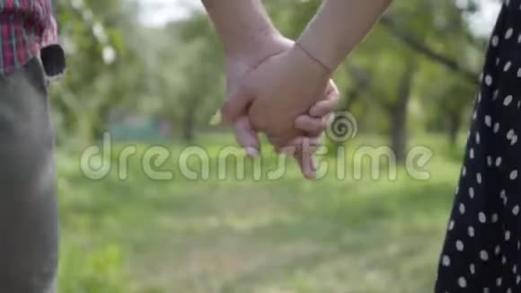一对年轻的积极夫妇牵着手走过花园快乐的男人和女人在户外视频的预览图