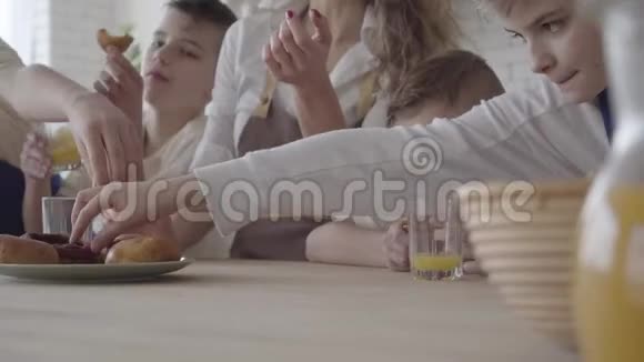 妈妈和她的四个十几岁的儿子正站在桌子旁吃着馅饼喝着橙汁视频的预览图