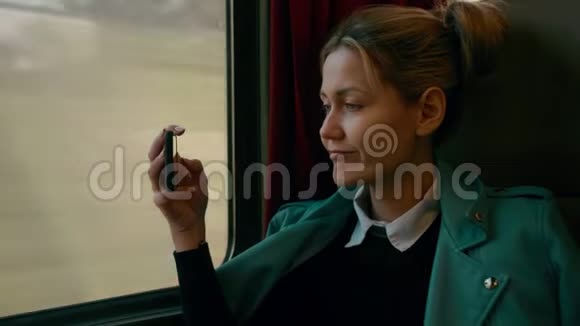 年轻的高加索商务女性正乘坐豪华的城际列车使用手机拍照慢慢视频的预览图