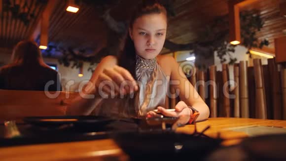 餐厅里的女孩戴着眼镜在智能手机上的社交网络上阅读信息视频的预览图