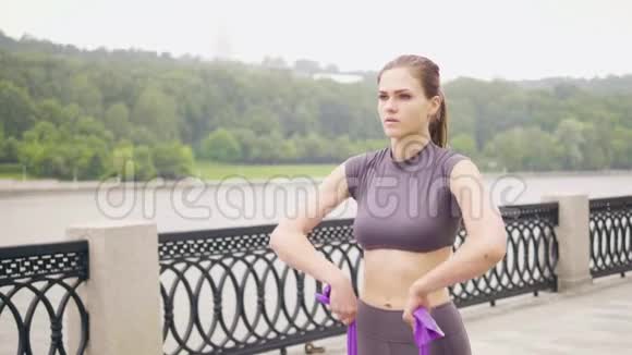 健身女孩在户外运动中进行阻力带训练视频的预览图