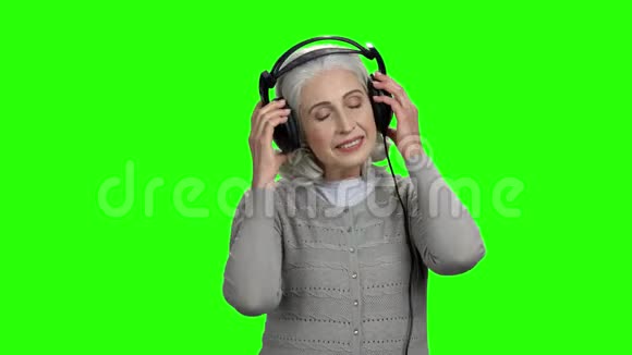 美丽的老年妇女听耳机音乐视频的预览图