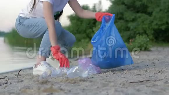 捡垃圾一位戴着橡胶手套的志愿者在清理海岸时把塑料垃圾收集到垃圾袋里视频的预览图
