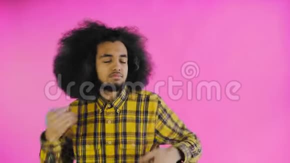 高兴地微笑着年轻的非洲男人在紫色的背景上跳舞情感概念视频的预览图