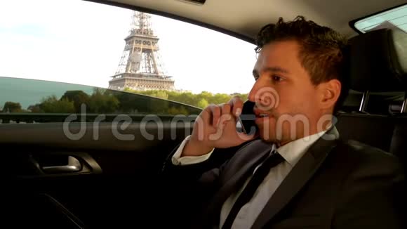 漂亮的年轻人穿着西装坐在埃菲尔铁塔旁边的车里视频的预览图