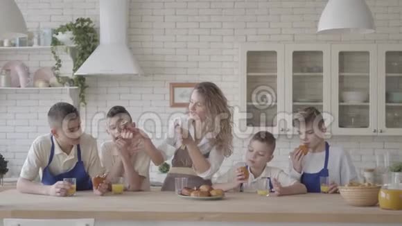 她和四个十几岁的儿子站在凯特肯身边吃馅饼喝橙汁视频的预览图