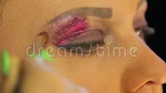 有刷子的雌手在眼睑上涂上明亮的淡紫色视频的预览图