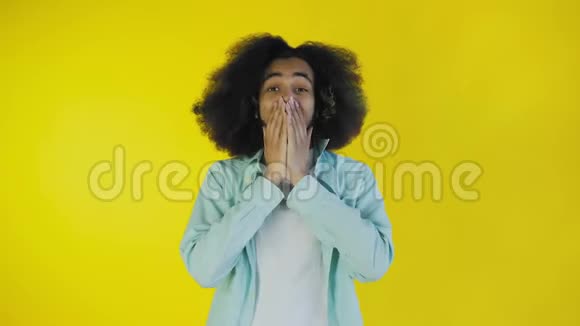 担心的非裔美国人笑着双手盯着她的脸在黄色的背景下庆祝成功视频的预览图
