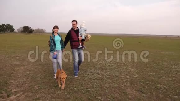 快乐的一家人带着一只带着背包的狗在野外旅行爸爸宝贝女儿和宠物狗游客的联合工作视频的预览图