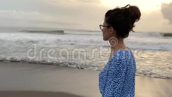 在波浪状的海底沙滩上散步的一个晒黑的女孩视频的预览图