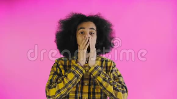 担心的非裔美国人笑着双手盯着她的脸在紫色的背景下庆祝成功视频的预览图