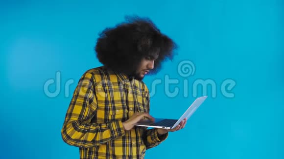 非裔美国人在笔记本电脑上打字不是摇头在蓝色背景上情感概念视频的预览图