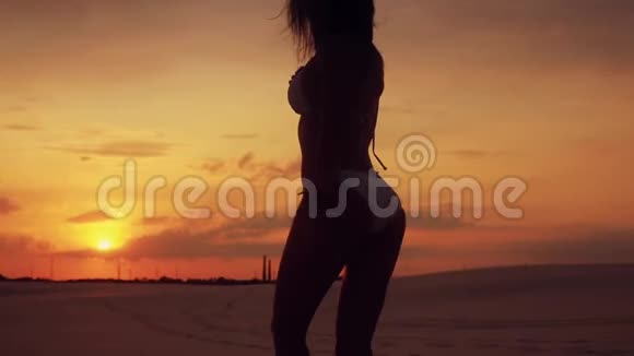 性感女人在沙漠中散步和摆姿势的剪影视频的预览图