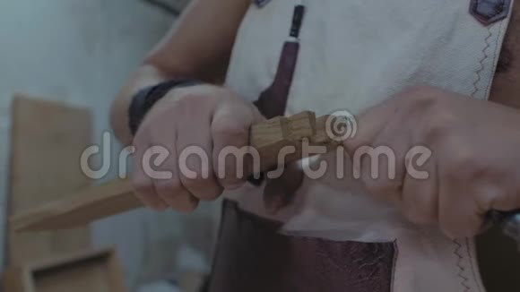 一个接头人用凿子把燕尾叼在木头上手里拿着木匠加工木板4k4k视频的预览图