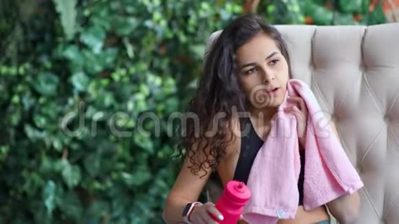 中度特写照片疲惫的年轻健身妇女用毛巾坐在沙发上视频的预览图