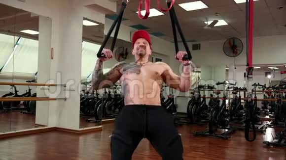 美丽的肌肉发达的运动男子收紧在悬挂的绳索增加肌肉视频的预览图