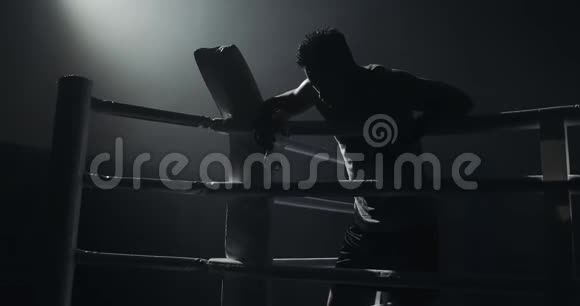 疲惫的男拳击手拿着一瓶水休息在戒指的话题上剪影拳击概念视频的预览图
