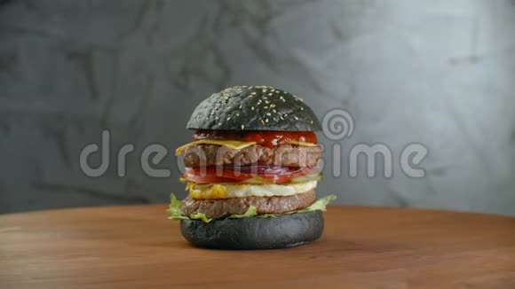 黑汉堡用格力蔬菜一个汉堡有两个切块旋转在一个木板上大肥汉堡视频的预览图