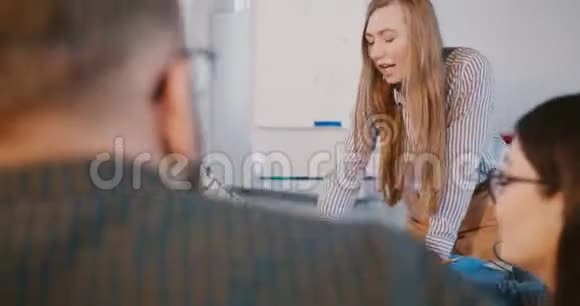 自信的金发商务女教练在现代健康办公室与员工交谈从男人背后看到视频的预览图