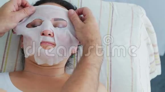 一位男性美容师将保湿面膜应用于水疗中心的女性客户视频的预览图