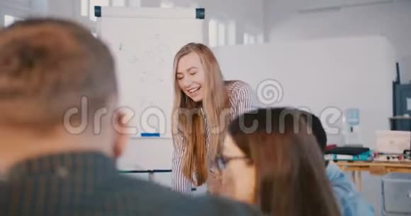 相机在现代健康办公室的团队会议上移动自信的金发商务女性与快乐的员工交谈视频的预览图